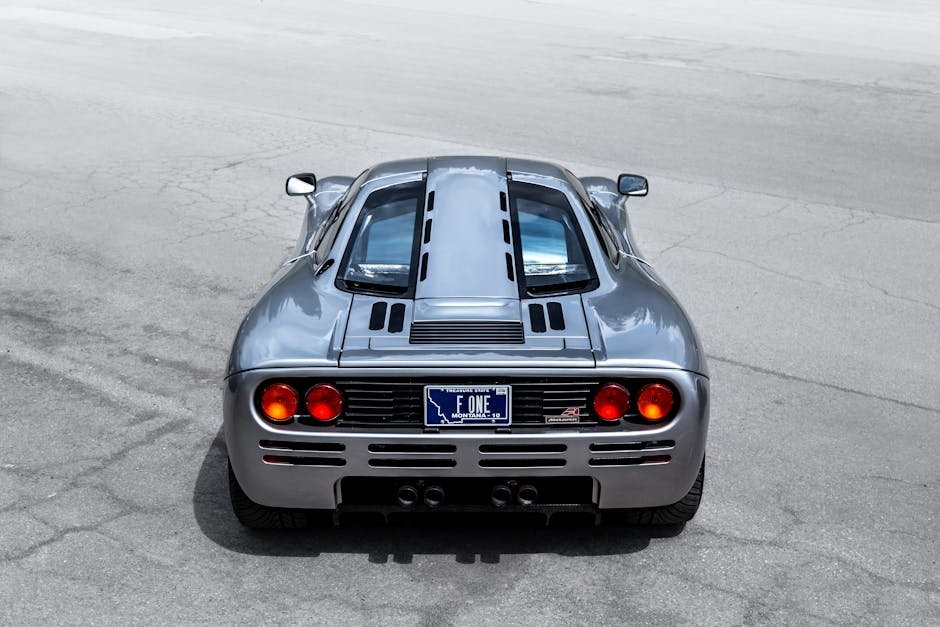 A sleek McLaren supercar captured from the rear on an open road, highlighting its design and elegance.