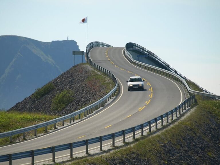 A car driving on the iconic Atlantic Ocean Road with coastal views and winding architecture.