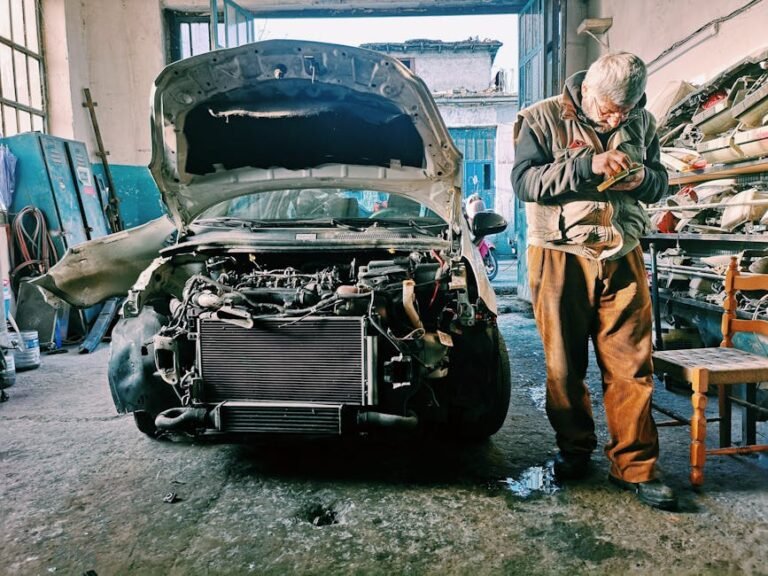 Mechanic repairing car in an auto workshop with the hood open showcasing the engine.