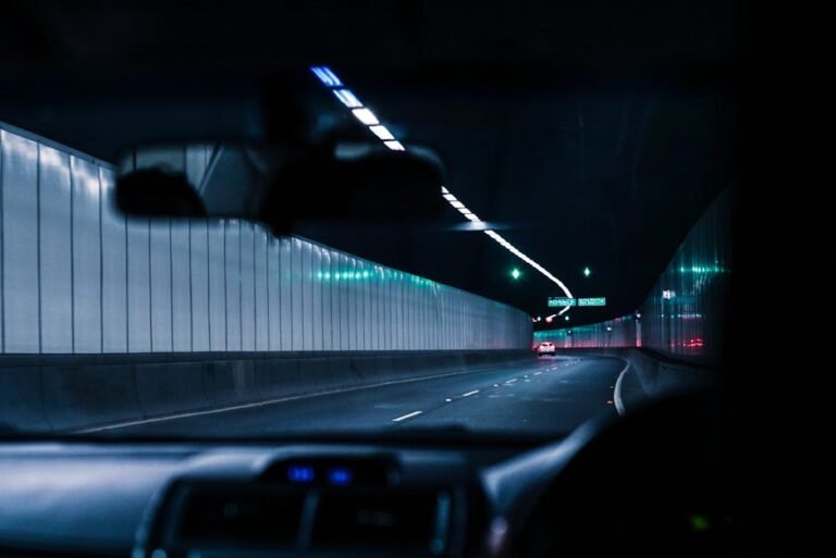 Inside view of a car driving through a brightly lit urban tunnel at night, showcasing modern transportation.