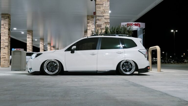 Sleek white car parked at a modern gas station at night.