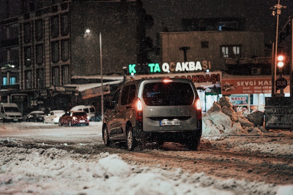 A car navigating snowy city streets at night during winter.