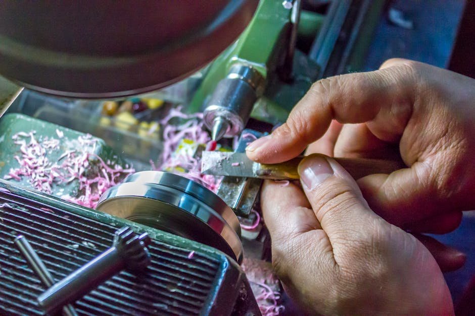 Hands carefully operate a metal lathe machine, showcasing precision in metalworking.