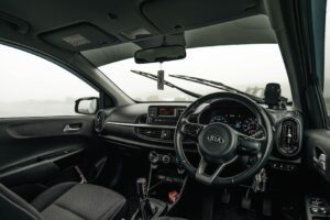 View of a Kia car interior with foggy landscape outside, showing the dashboard and steering wheel.