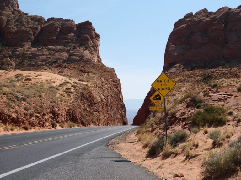A picturesque road cutting through a rocky desert canyon under a clear blue sky.