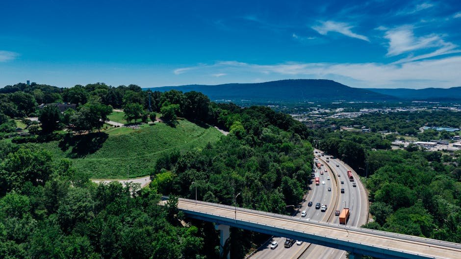 Aerial view of Chattanooga's lush greenery, highway, and distant mountains on a sunny day.